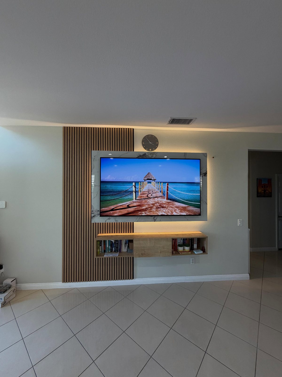 A television mounted on a wall featuring a vertical wooden slat accent panel.