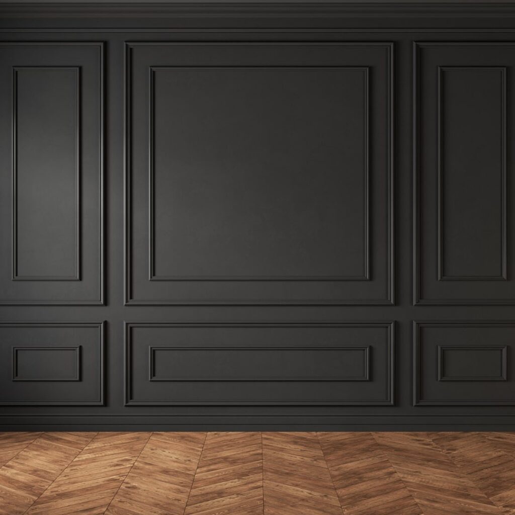 Dark charcoal grey wall with decorative picture frame molding and herringbone wood flooring.