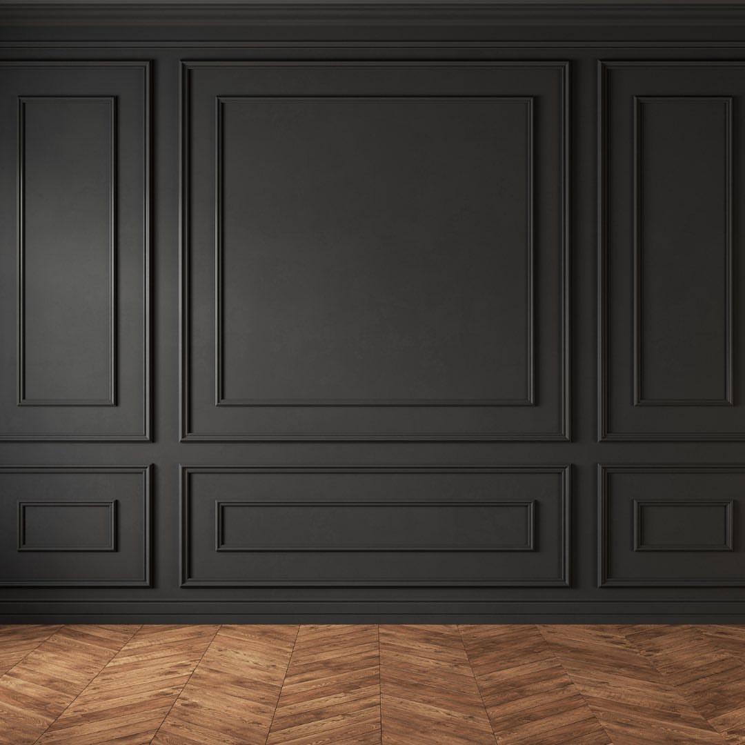Dark charcoal grey wall with decorative picture frame molding and herringbone wood flooring.