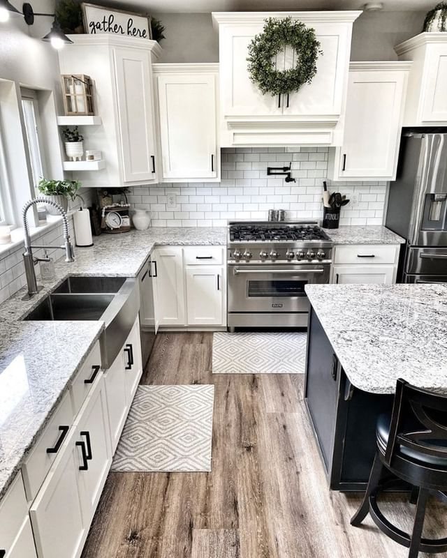 White kitchen cabinets with granite countertops and wood-look plank flooring in a bright room.