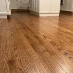 Polished oak hardwood flooring with a warm medium brown stain in a kitchen setting.