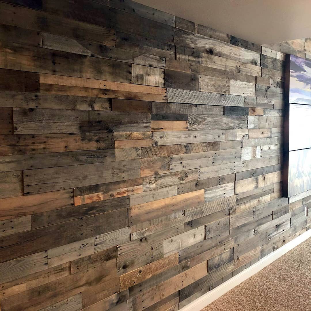 Distressed wood shiplap planks in various natural tones covering a large interior accent wall.