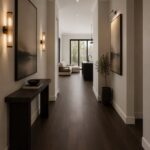 Dark wood flooring running through a long, modern hallway with white walls and minimalist furniture.